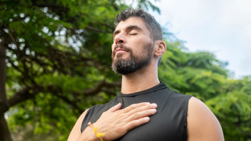Homme pratiquant une respiration profonde en plein air, une main posée sur la poitrine