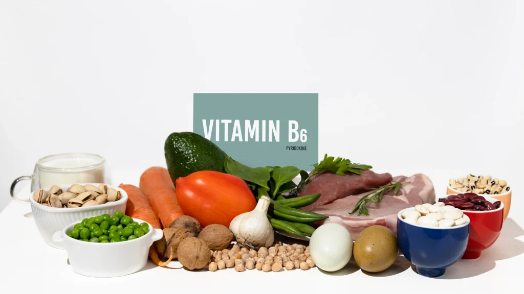 Quels aliments apportent de la vitamine B6 Viandes, légumineuses, fruits à coque et légumes disposés devant un panneau « Vitamin B6 ».