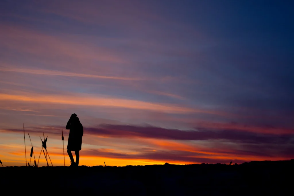 Silhouette masculine immobile au coucher du soleil, représentant la diminution de l’adrénaline chronique et un environnement favorable au maintien de la testostérone.